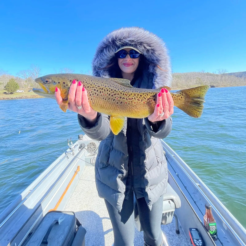 Angler holding a brown trout on the lake